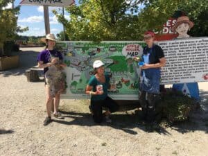 Three painters posing with their paint cans and paint brushes in front of a big hand-painted map.