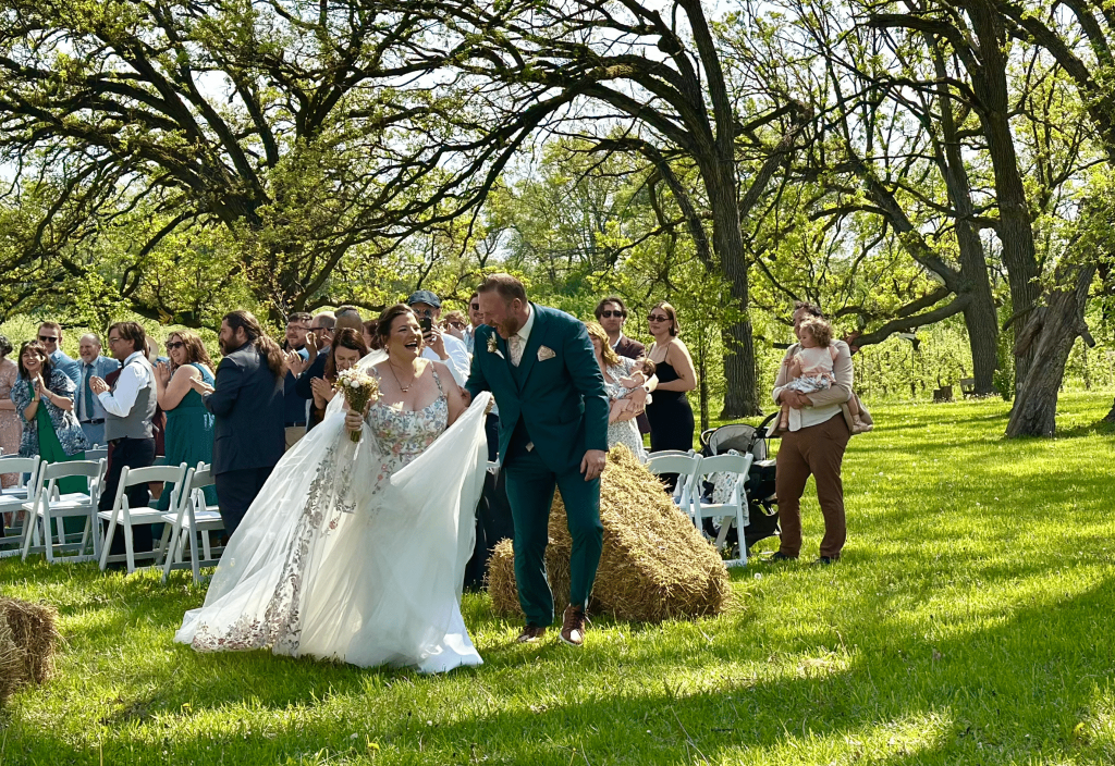 Bride and groom smiling at each other as they walk out of the isle of their wedding.